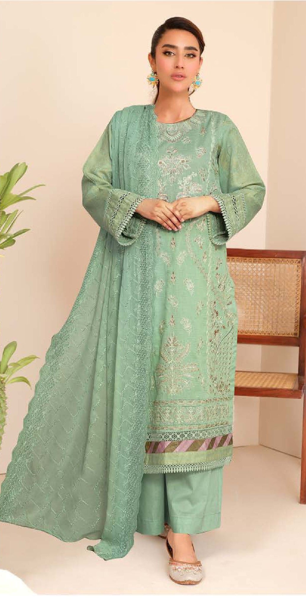 Woman wearing a green embroidered traditional outfit with a beige background