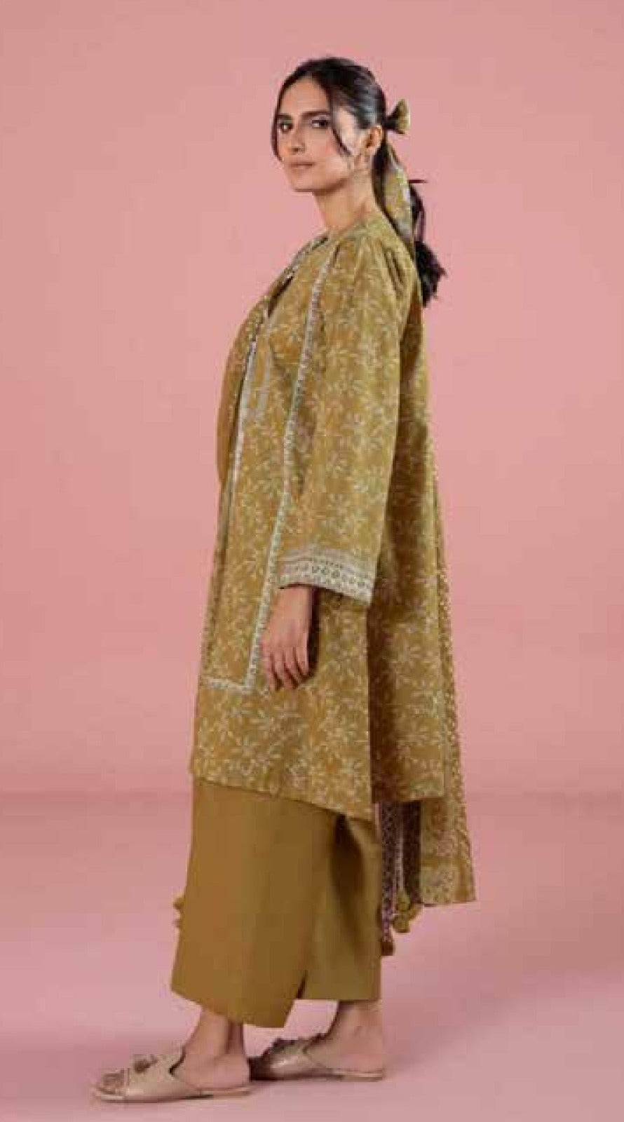 Woman wearing a green traditional outfit with a pink background