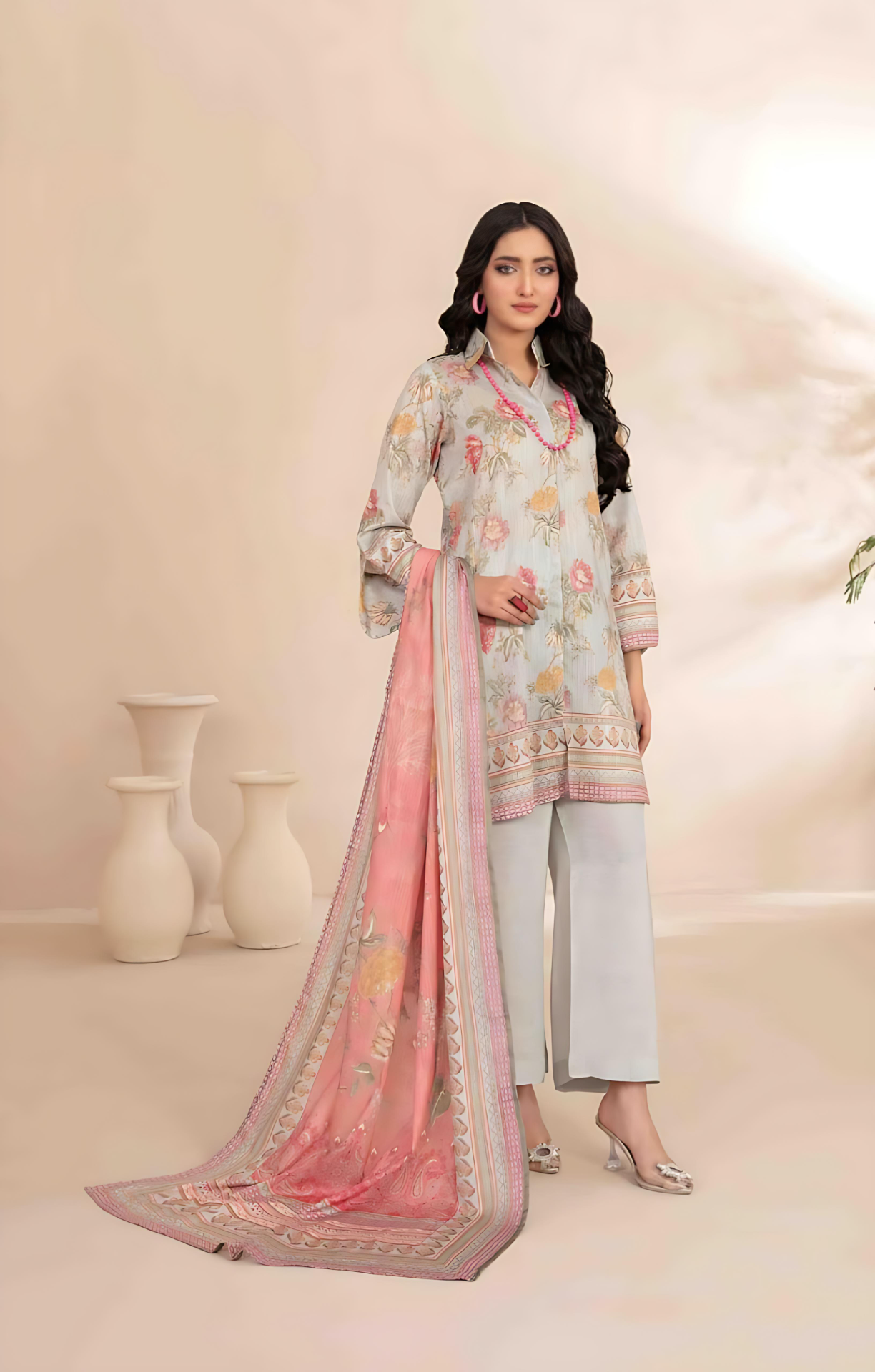 Woman wearing a light blue printed suit with a pink dupatta on a beige background