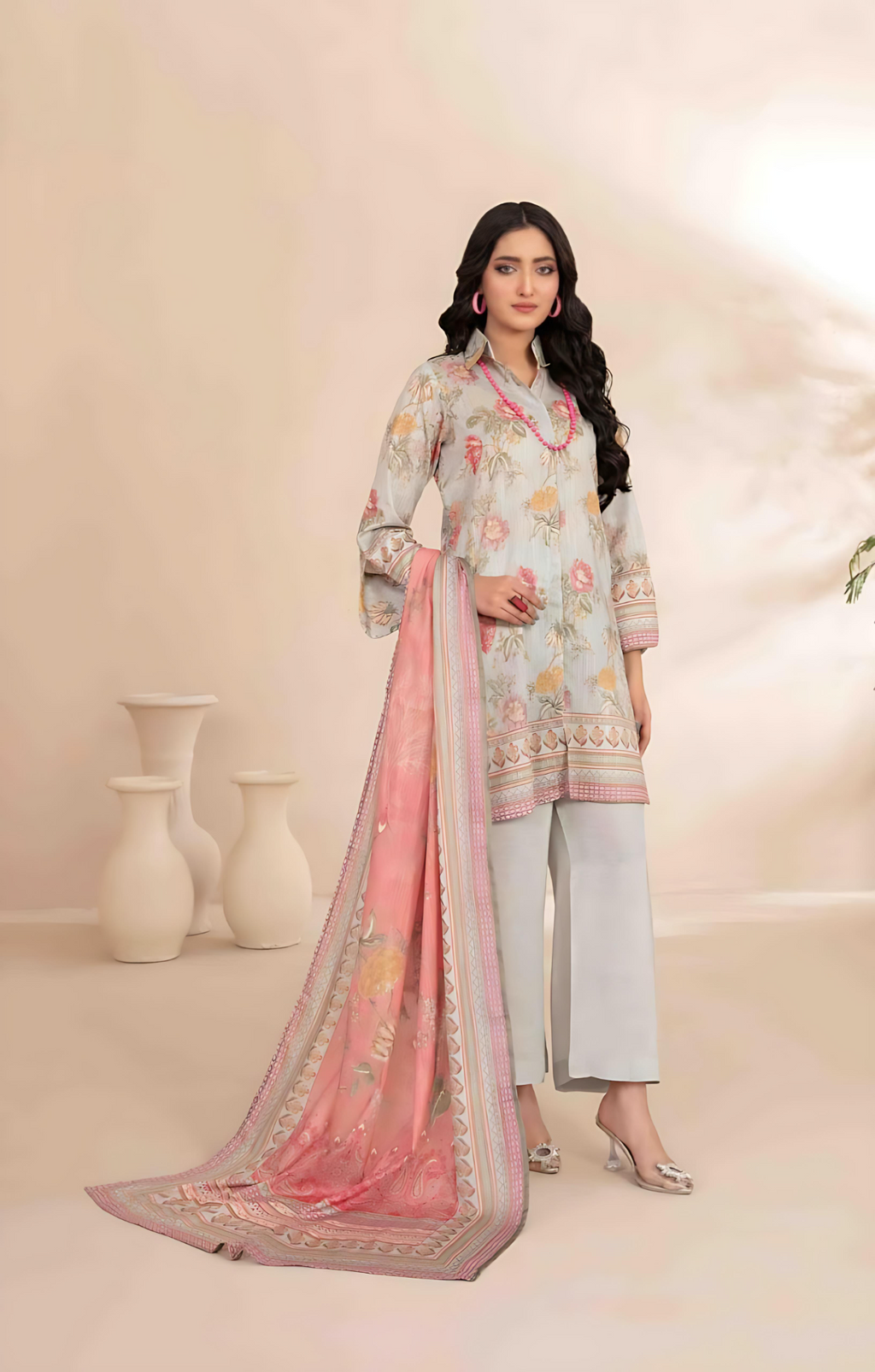 Woman wearing a light blue printed suit with a pink dupatta on a beige background