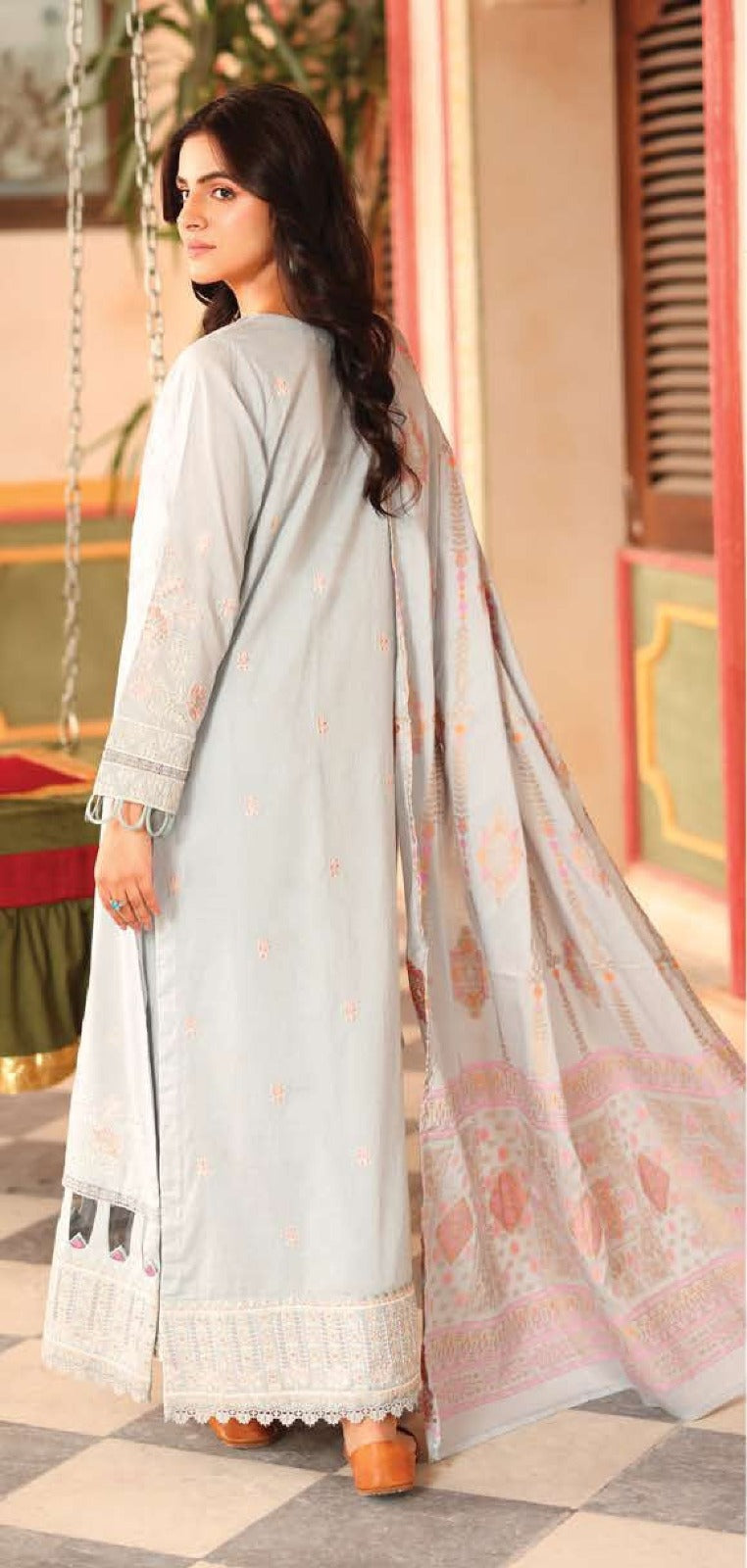 Woman wearing a light blue traditional outfit with a floral dupatta in an outdoor setting.