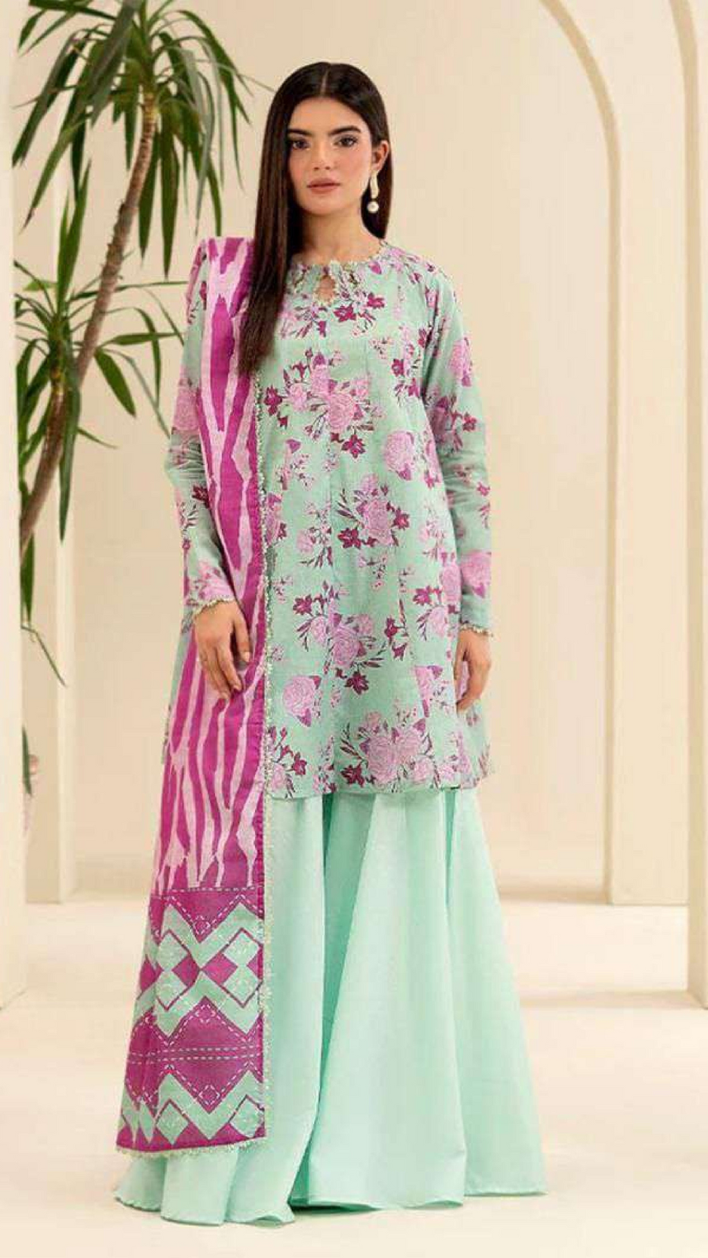 Woman wearing a light green and pink floral printed outfit with a geometric patterned dupatta.