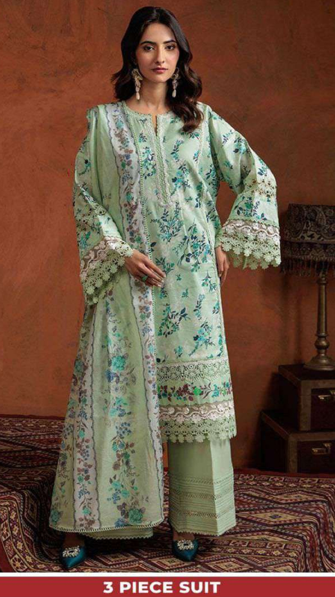 Woman wearing a light green floral printed suit against an orange wall.