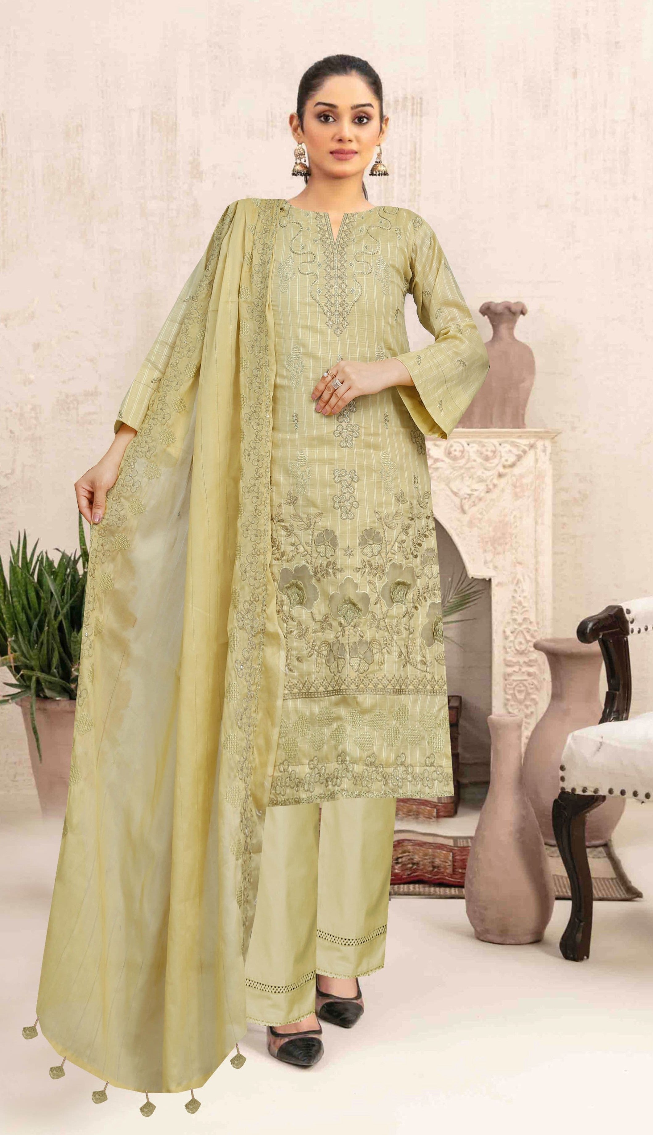 Woman wearing a light green traditional outfit with a dupatta in an indoor setting.