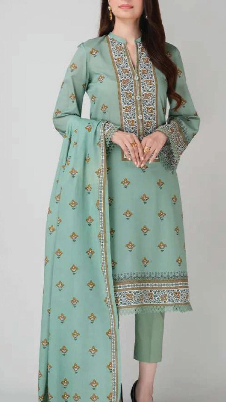 Woman wearing a light green traditional outfit with intricate patterns on a plain background