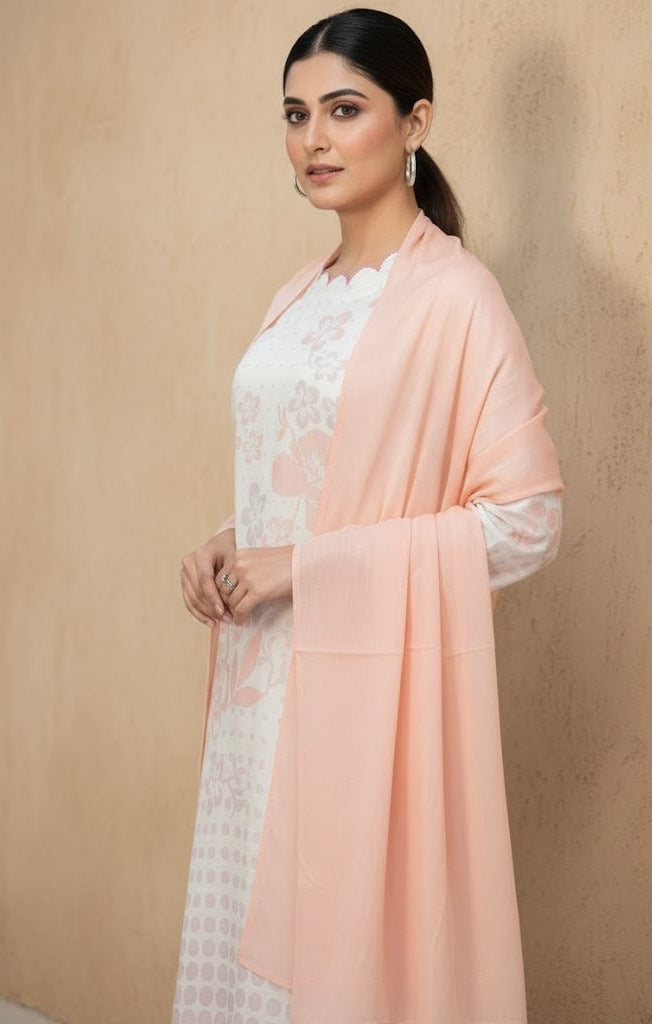 Woman wearing a light pink dupatta over a white outfit against a beige background