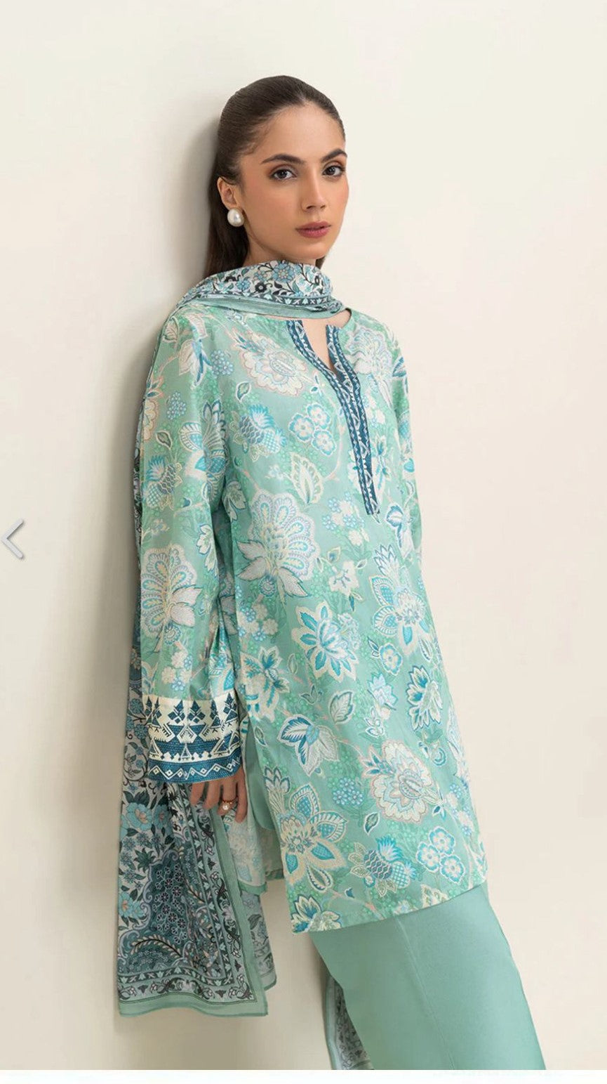 Woman wearing a light seagreen printed traditional outfit on a white background