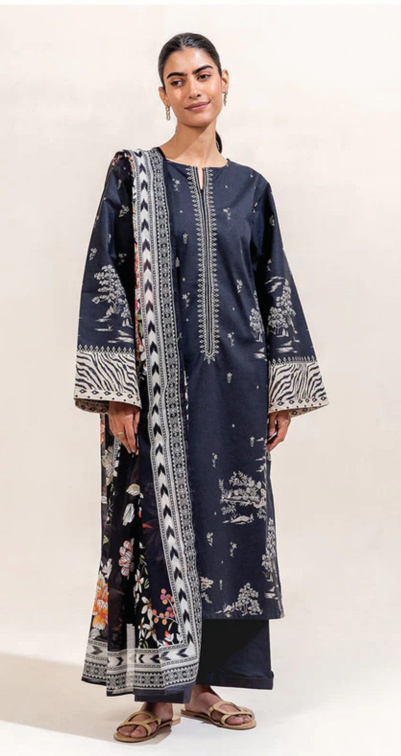 Woman wearing a long, dark blue dress with white patterns on a plain background