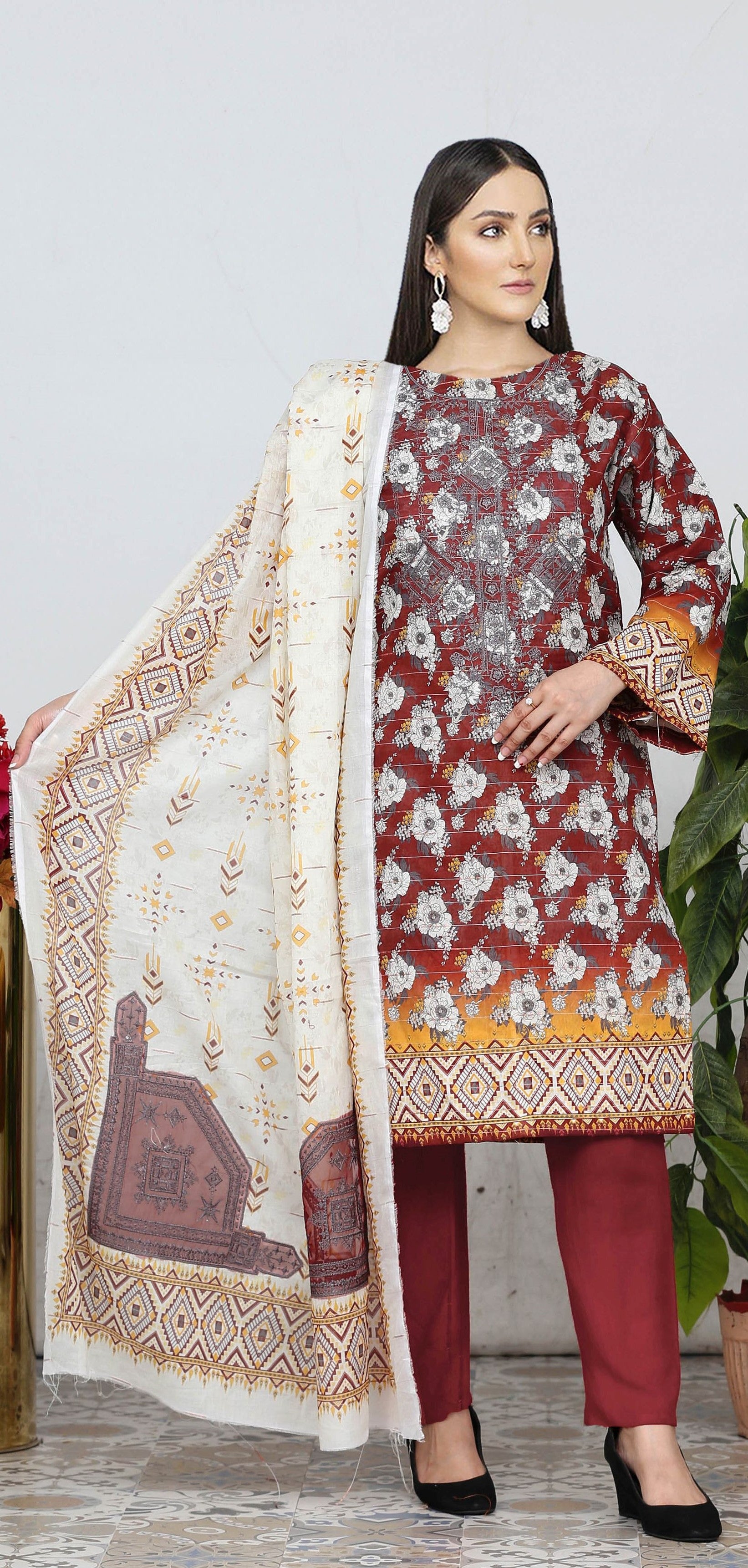 Woman wearing a maroon floral dress with a matching dupatta against a white background