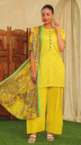 Woman wearing a mor e bagh  bright yellow traditional outfit with a green dupatta against a neutral background