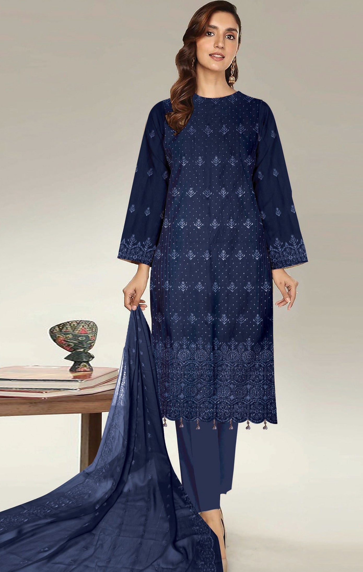 Woman wearing a navy blue embroidered outfit with a table and decorative items in the background