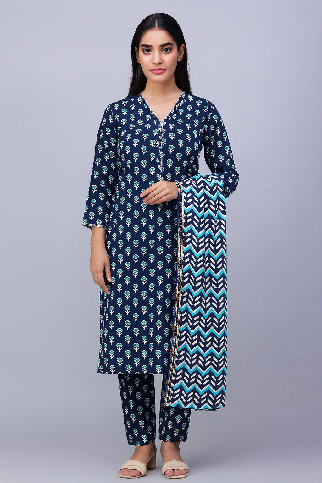 Woman wearing a navy blue printed outfit with a printed dupatta on a gray background