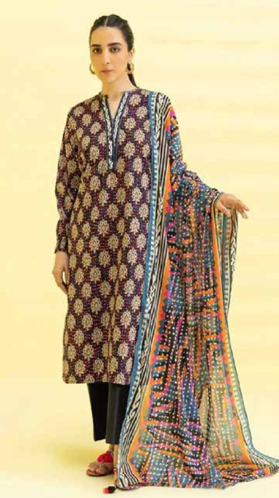 Woman wearing a patterned kurta with a matching dupatta on a beige background