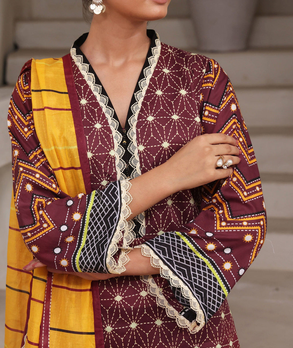 Woman wearing a patterned outfit with a yellow and maroon design.