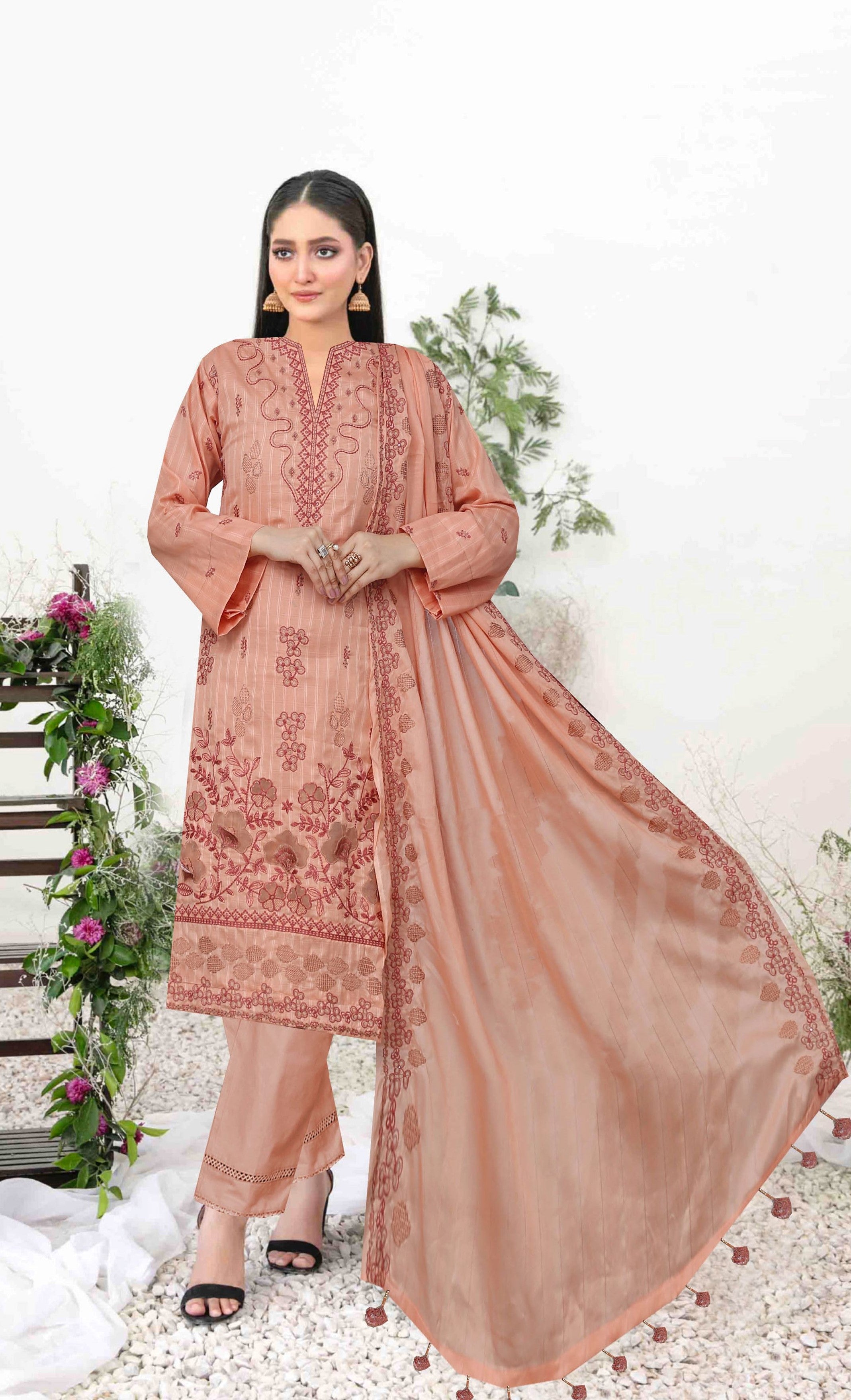 Woman wearing a peach-colored embroidered traditional outfit with a white background