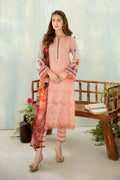 Woman wearing a pink traditional outfit with floral patterns in a minimalistic setting.