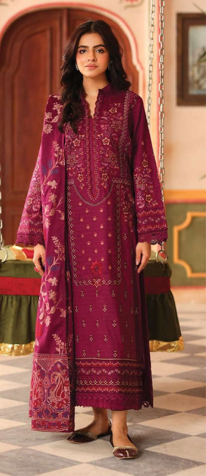 Woman wearing a purple embroidered traditional outfit in an ornate indoor setting.
