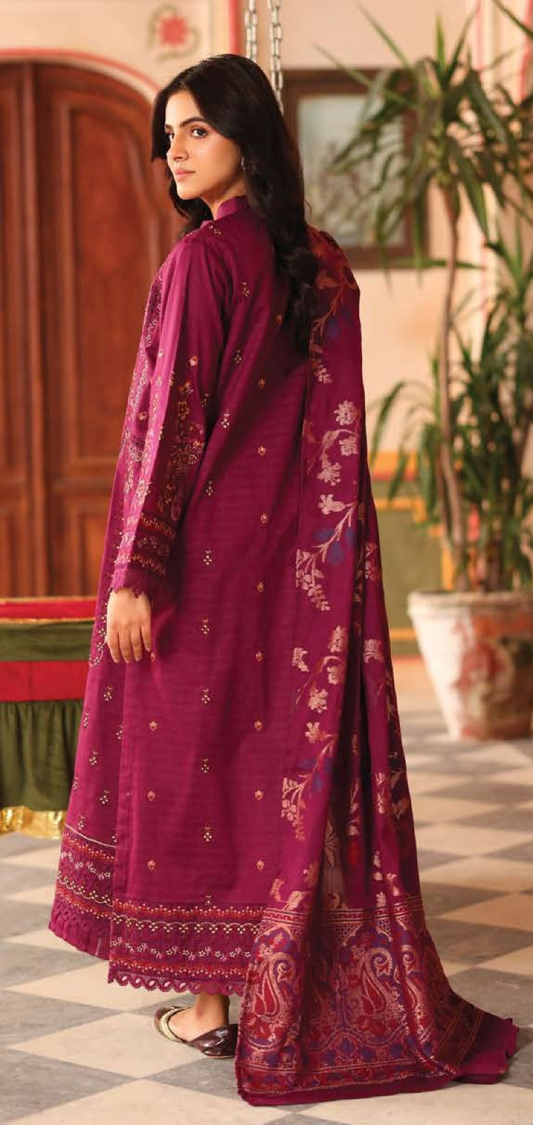 Woman wearing a purple traditional outfit with a matching dupatta indoors.