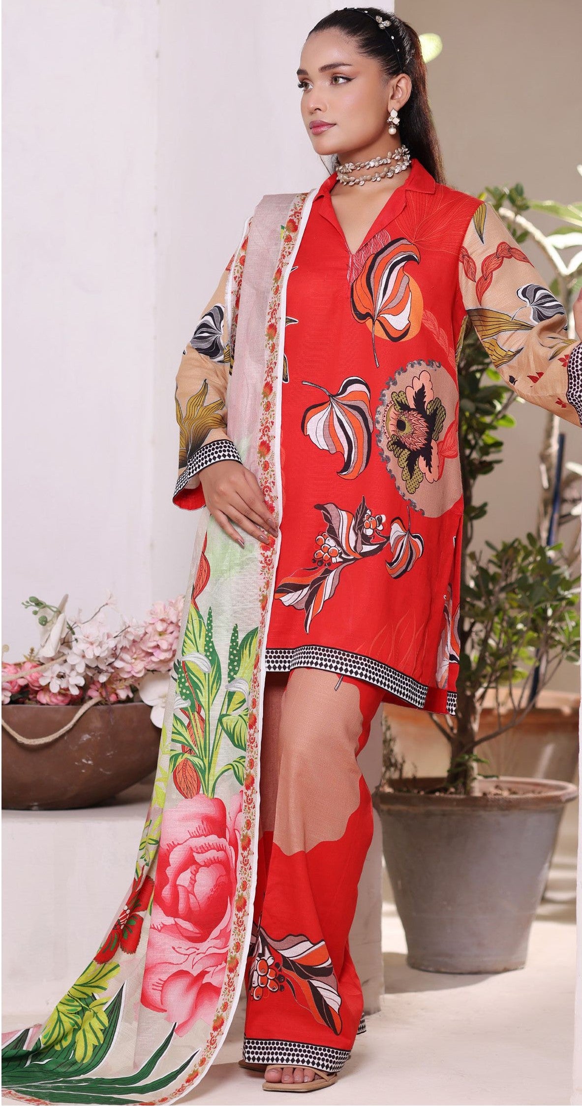 Woman wearing a red floral outfit with a matching Dupatta in an indoor setting.