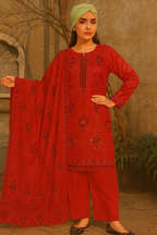 Woman wearing a red embroidered outfit with a green headscarf in an outdoor setting.