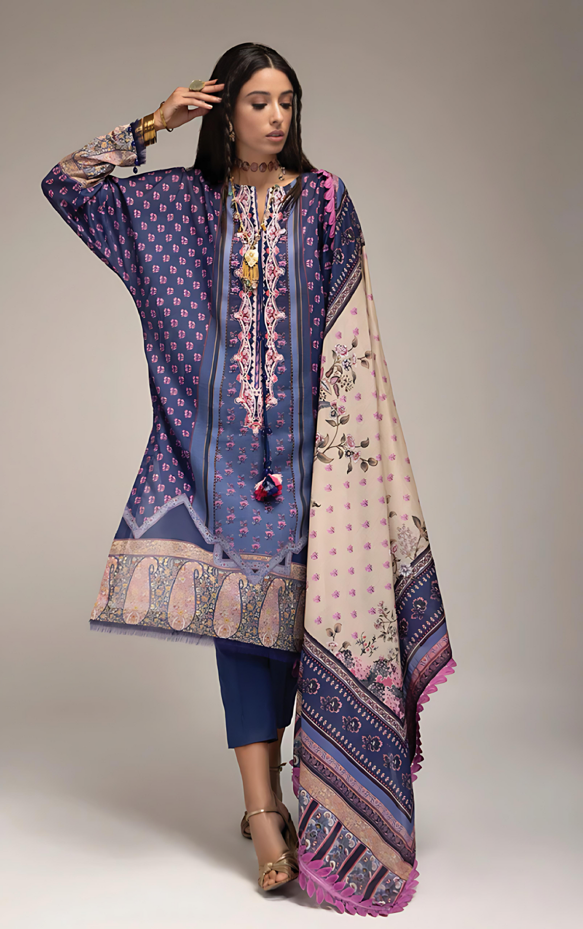 Woman wearing a sobia_nazir traditional outfit with a patterned dupatta on a plain background