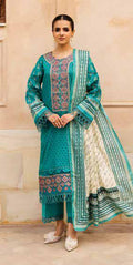 Woman wearing a teal embroidered traditional outfit with a matching dupatta against a beige wall.