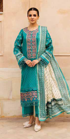 Woman wearing a teal embroidered traditional outfit with a matching dupatta against a beige wall.