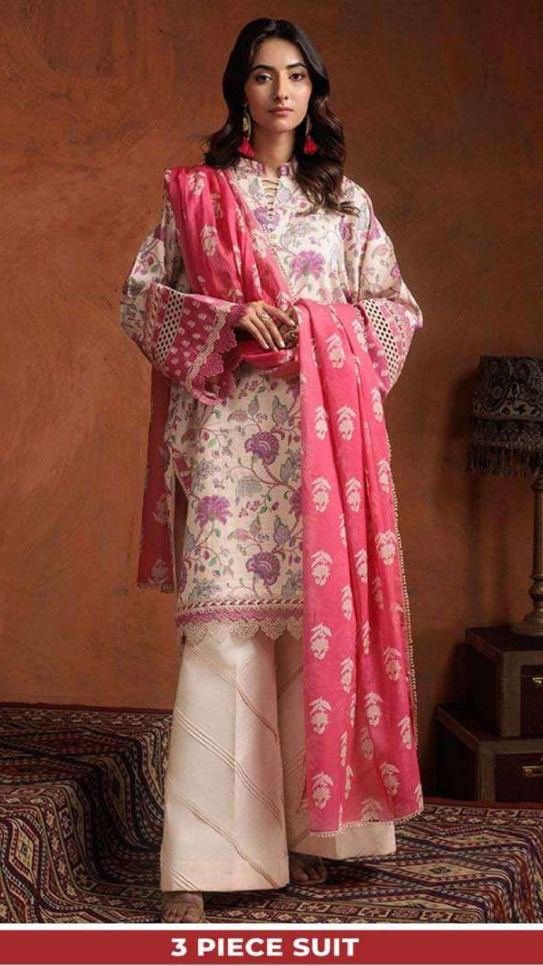 Woman wearing a three-piece suit with a pink and white floral pattern against a warm-toned wall.