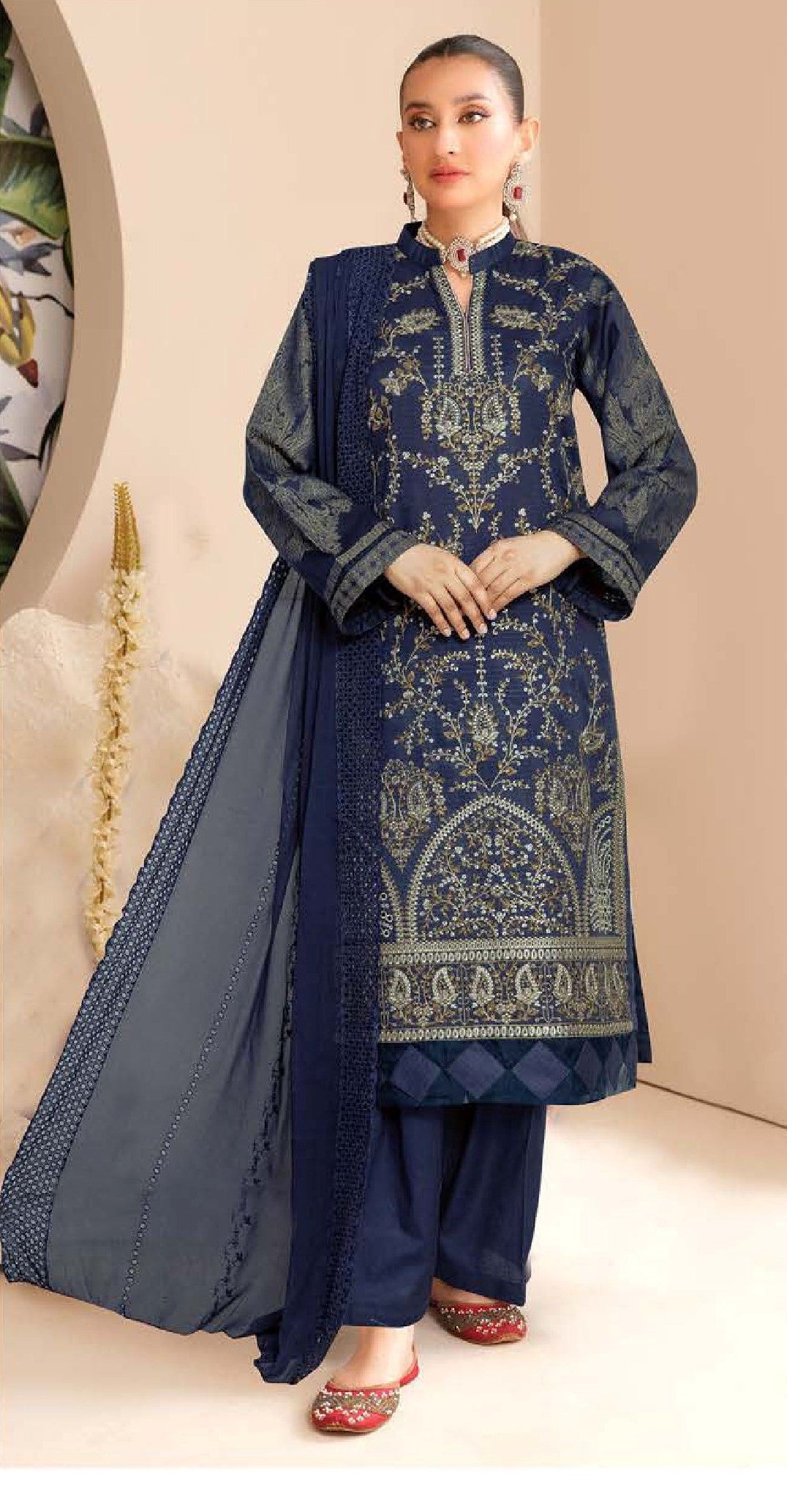 Woman wearing a traditional blue embroidered outfit with a matching dupatta on a beige background