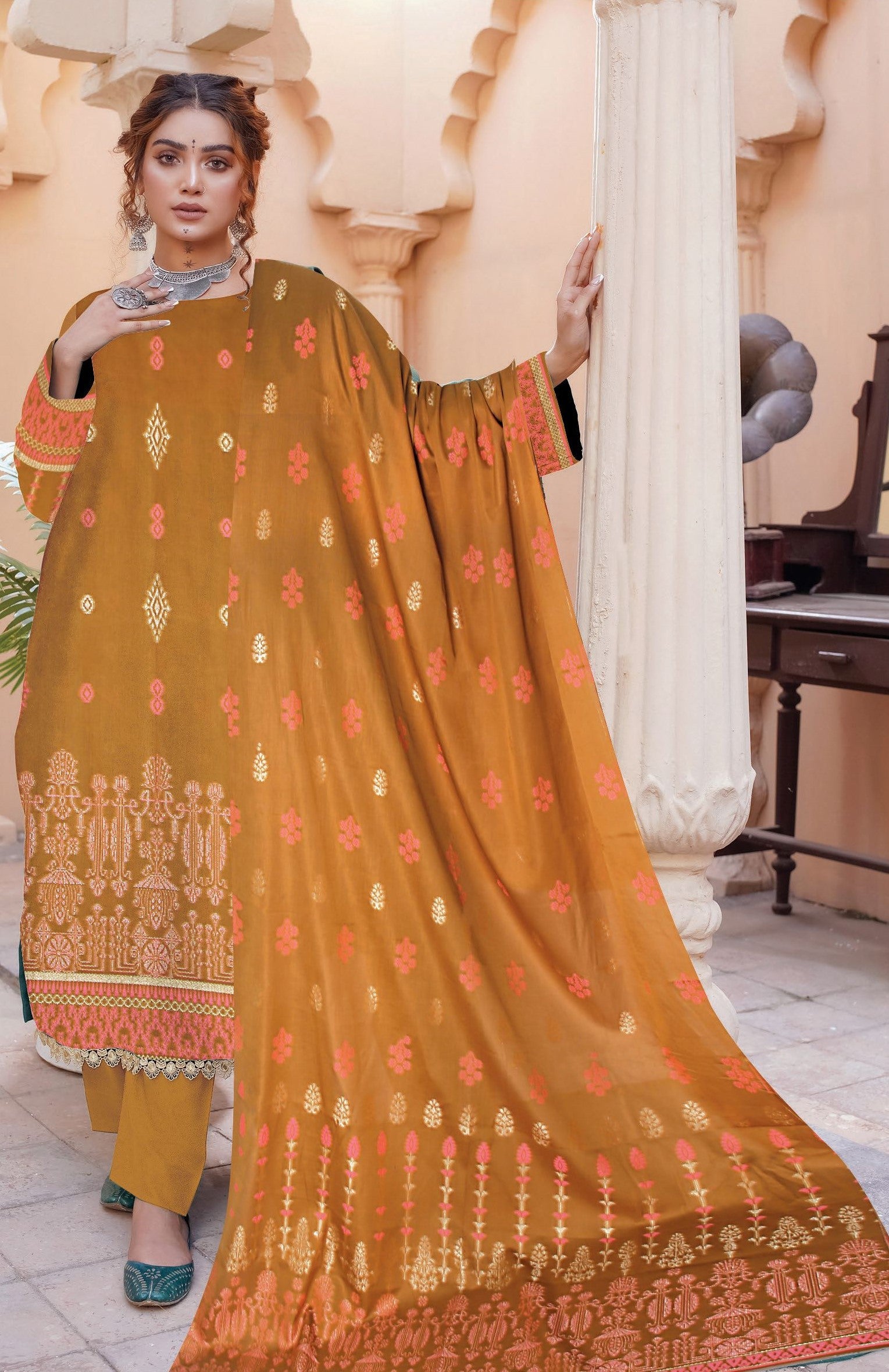 Woman wearing a traditional outfit with a mustard yellow dupatta in an indoor setting.