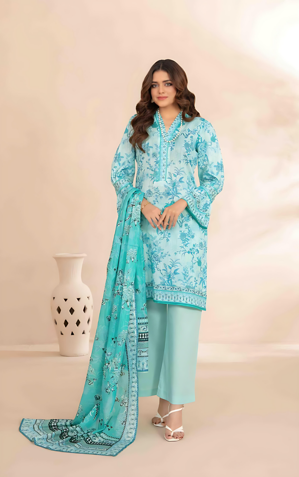 Woman wearing a turquoise printed outfit with a matching dupatta on a beige background