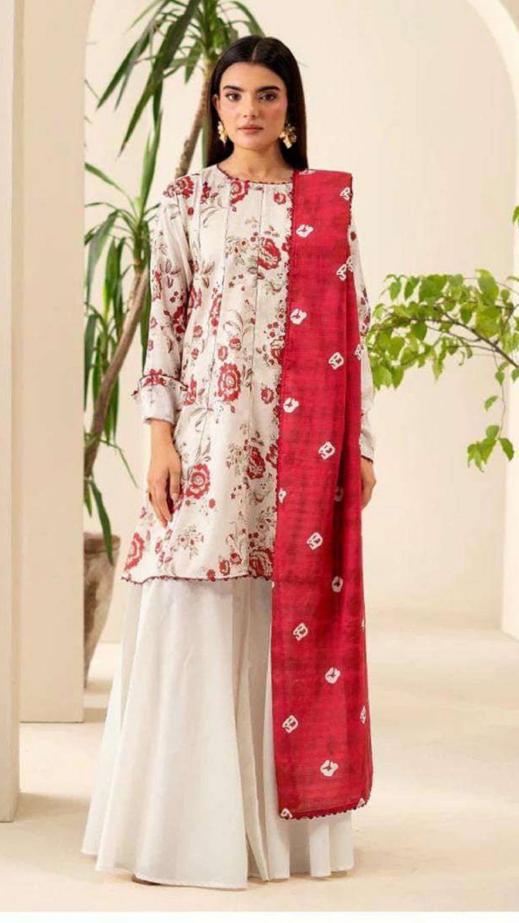 Woman wearing a white floral kurta with red dupatta in an indoor setting