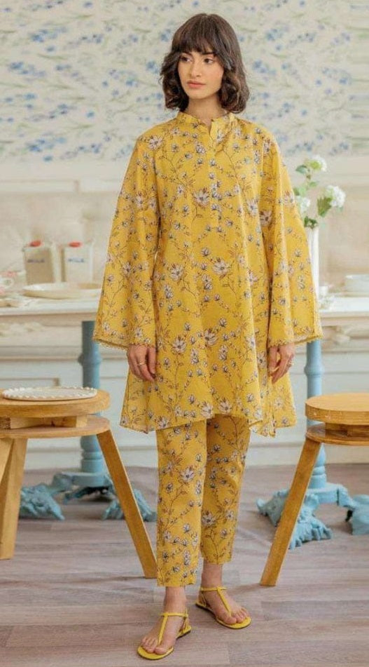 Woman wearing a yellow floral outfit in a room with wooden furniture and decorative elements.