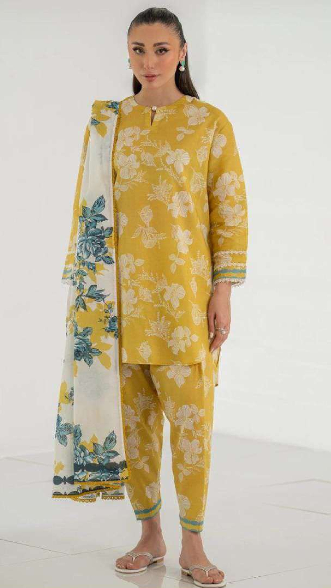 Woman wearing a yellow floral outfit with a matching dupatta on a white background