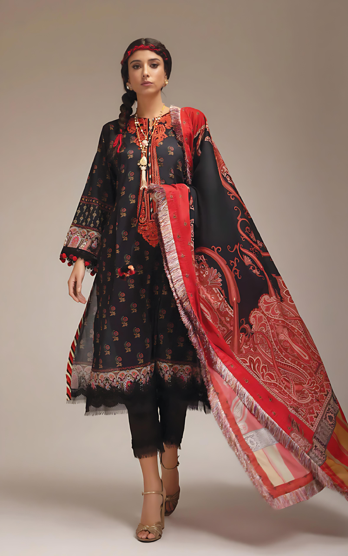 Woman wearing sobia_nazir a traditional outfit with a black and red patterned dress and dupatta on a neutral background