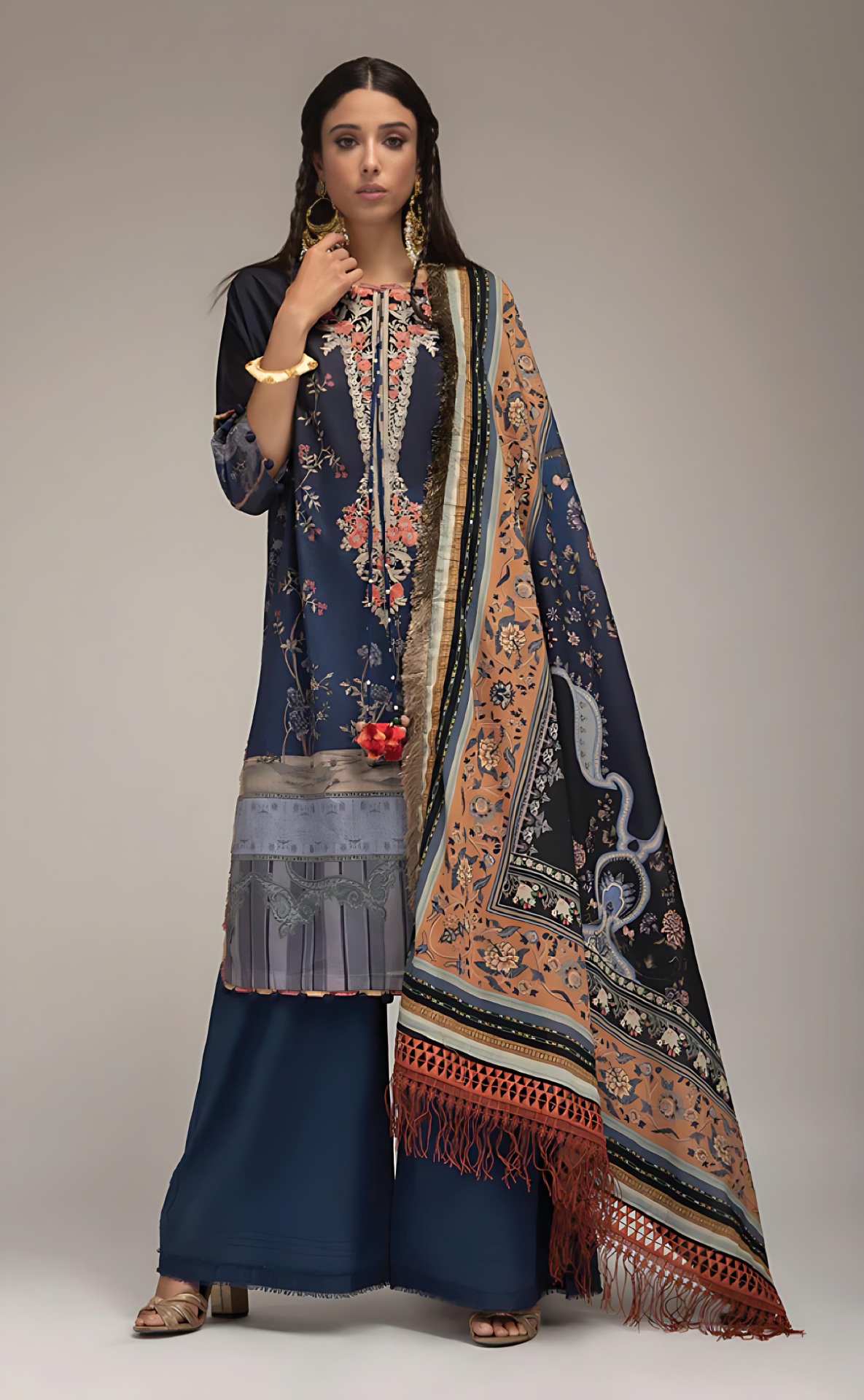 Woman wearing sobia_nazir a traditional outfit with a dark blue printed dress and patterned dupatta on a neutral background