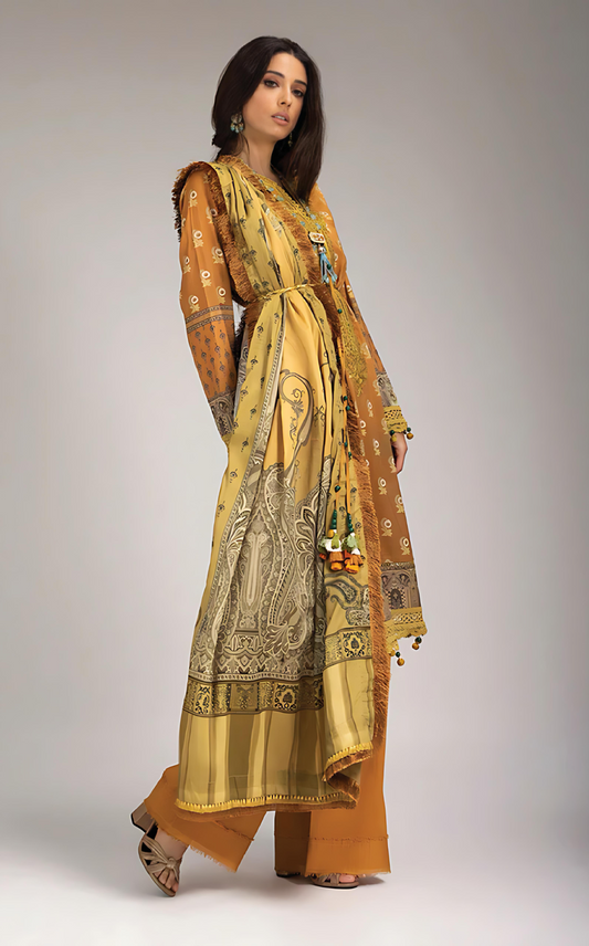 Woman wearing sobia nazir long, patterned yellow dress with a matching dupatta on a gray backgrounda 