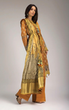 Woman wearing sobia nazir long, patterned yellow dress with a matching dupatta on a gray backgrounda 