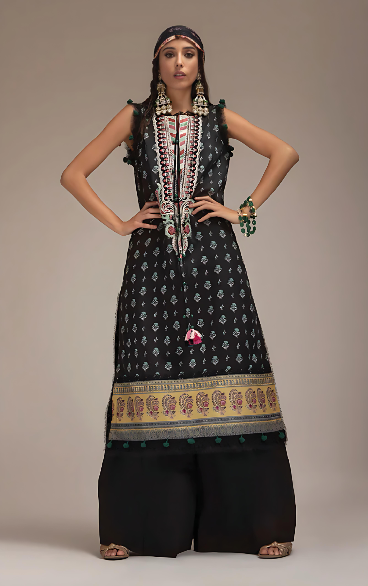 Woman wearing sobia nazir traditional black patterned outfit with jewelry against a neutral background