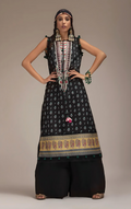 Woman wearing sobia nazir traditional black patterned outfit with jewelry against a neutral background