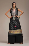 Woman wearing sobia nazir traditional black patterned outfit with jewelry against a neutral background