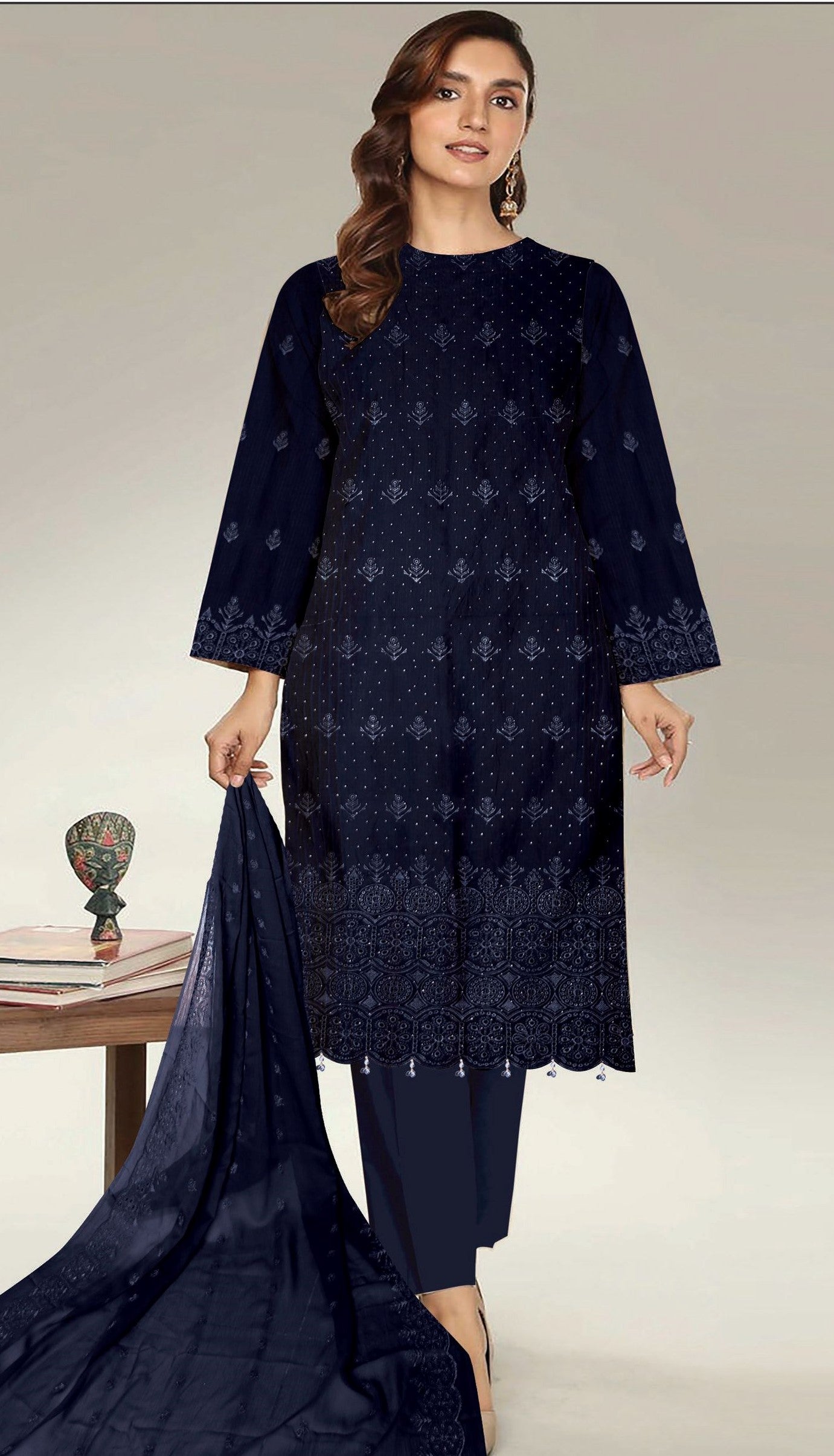 Woman wearing a navy blue embroidered outfit on a plain background