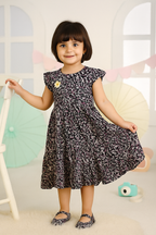 Young girl in a patterned dress standing in a room with colorful decorations.