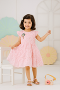 Young girl in a pink dress standing in a room with colorful umbrellas in the background