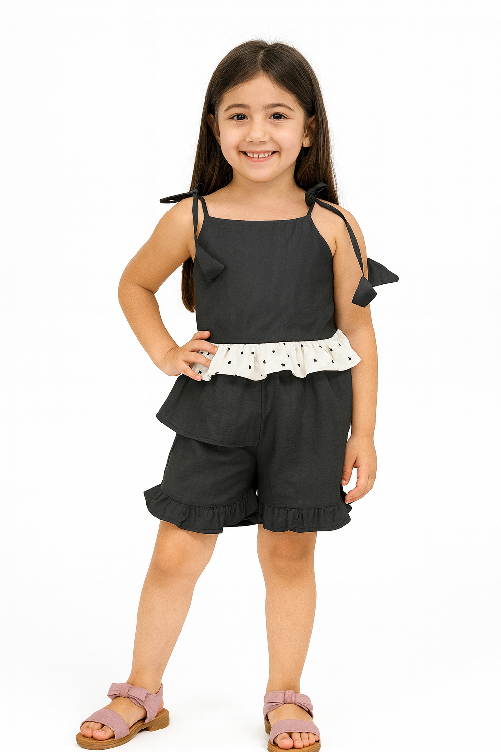 Young girl wearing a black outfit with white polka dot trim on a white background