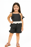 Young girl wearing a black outfit with white polka dot trim on a white background