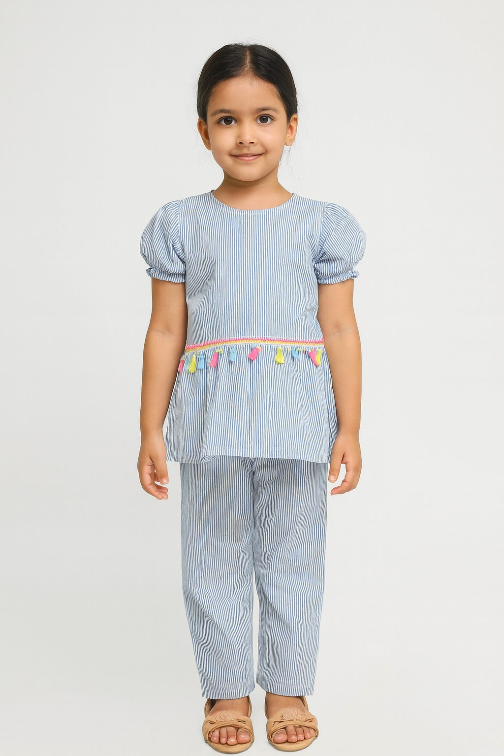 Young girl wearing a light blue striped outfit with colorful trim on a white background