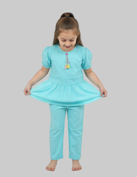 Young girl wearing a matching turquoise top and pants set on a gray background