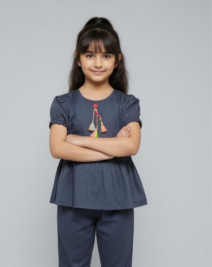Young girl wearing a navy blue top and pants with a plain background