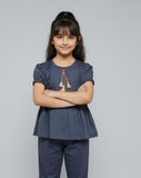 Young girl wearing a navy blue top and pants with a plain background